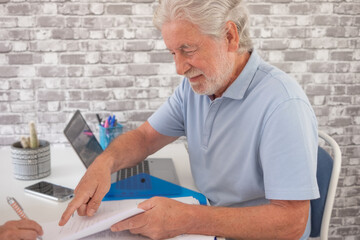 Handsome senior business man in office finishing the contract with a client asking for a signature, smiling caucasian people sitting at the desk
