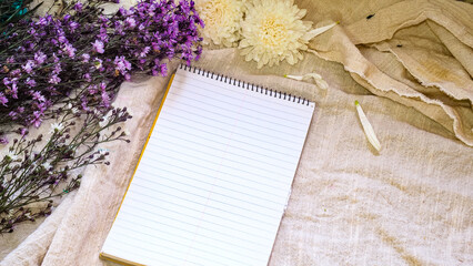 Blank paper  and flower decoration. Greeting card on a white natura; linen background. Top view. Copy space