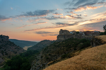 Fototapeta premium Panoramic view of a sunrise between mountains, with a town on the mountain