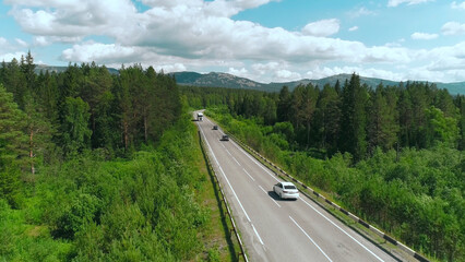 Top view of truck driving along highway on summer day. Scene. White truck is driving on country highway with green wooded area. Truckers and moving trucks in summer