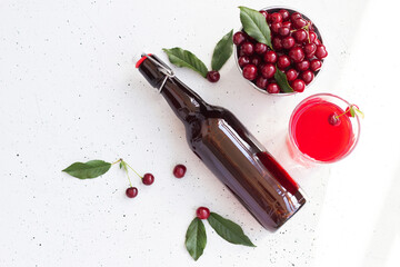 Cold cherry juice in a glass and bottle with ripe berries. Top view, copy space for text. The concept of summer refreshing drink morse or kompot. © Лариса Андреева