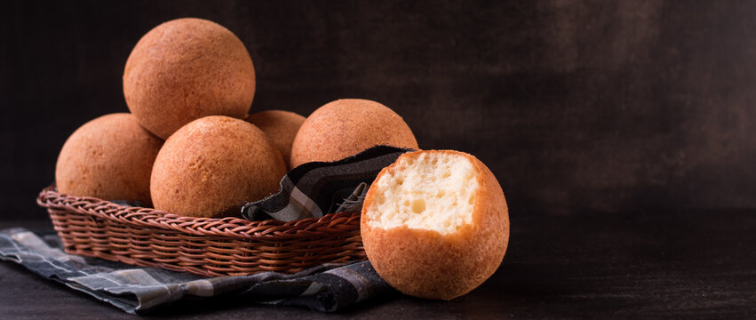 Round colombian traditional food named bu&ntilde;uelo in a basket on black wooden table 
