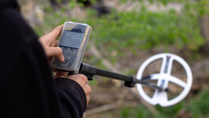 A man sets up a wireless metal detector to search for treasures underground.  Metal detector coil out of focus