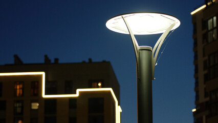 Close up city courtyard with street lamp on a dark blue sky background. Stock footage. Late evening landscape outdoors with an apartment building.