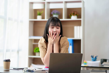 Cheerful and beautiful Asian businesswoman is very excited and delighted because she is satisfied with the work she has accomplished achieve your goals with your laptop computer.