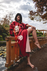 Portrait of sexy and young japanese girl with beautiful old traditional red kimono and handmade cat...