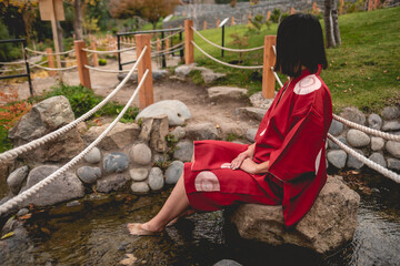 Portrait of sexy and young japanese girl with beautiful old traditional red kimono sitting on a...