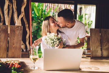 Romantic Caucaisan man making surprise present of beautiful wildflowers to wife working as...