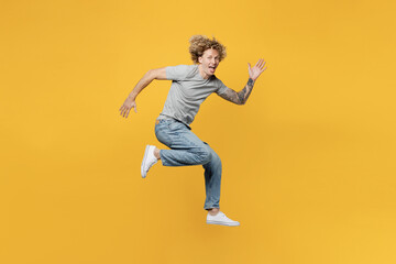 Fototapeta na wymiar Full body side view young strong sporty caucasian man 20s he wear grey t-shirt look camera jump high run fast look camera isolated on plain yellow backround studio portrait. People lifestyle concept.