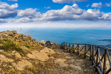Fototapeta premium mountain landscape with a hiking trail leading to a mountain town and beautiful blue seashore far away