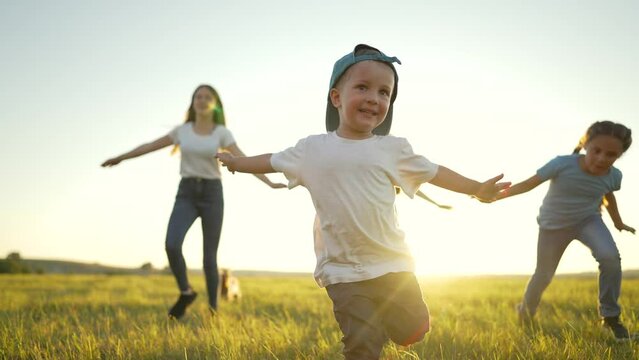 Happy family concept.Child run hand to the sides in park.Child play with dog in field on green grass.Family games of friend at sunset.Dream kid in summer in park.Family jogging in green grass with dog