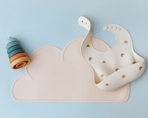 Silicone bib on light blue background, flat lay. Serving baby food, first feeding concept. Flat lay, copy space, top view