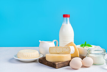 Dairy products and eggs on a blue background. Different kinds of cheese, milk, cream and eggs on a blue background. Side view, copy space.