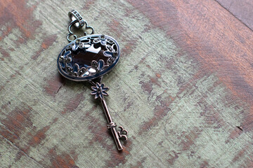 black and silver key on a wooden table. Necklace pendant.