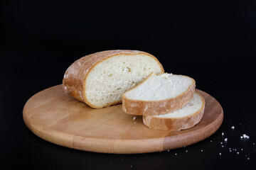 Freshly baked Bread, sliced with a serrated bread knife on a wooden cutting board