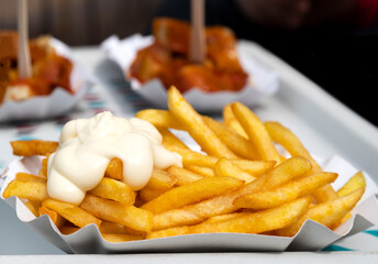 Close-up of an isolated greasy, unhealthy snack: fries with mayonnaise in a paper bowl. In the...
