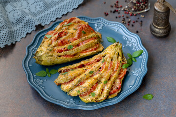 Roasted zucchini or summer squash stuffed with tomatoes, cheese and fresh herbs on a plate.