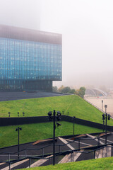 Katowice, Poland - 14 October 2021: Cultural Center in Katowice. View towards a modern skyscraper on a hazy day. Green roofs in the foreground.