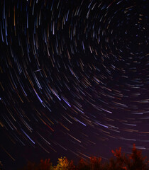 Star trails in the night sky with long exposure. Movement of stars over the Earth. Lines of colored stars. Polar Star. Starry background