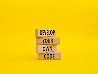 Develop your own code symbol. Concept words Develop your own code on wooden blocks. Beautiful yellow background. Business and Develop your own code concept. Copy space.