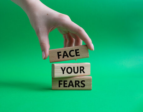 Face your Fears symbol. Wooden blocks with words Face your Fears. Beautiful green background. Businessman hand. Business and Face your Fears. Copy space.