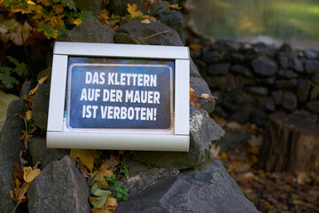 Schild an einer Mauer in einem Park mit den Worten das Klettern auf der Mauer ist verboten