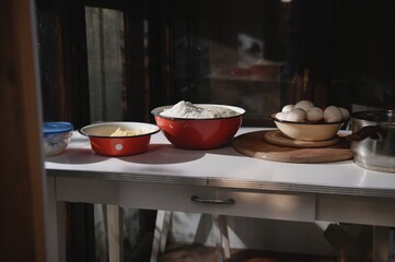 Assortment of fresh pizza ingredients in enamel vintage bowls on a white table in a rustic country house kitchen.