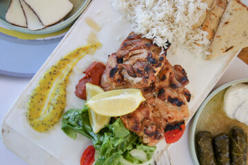 Chicken leg fillet served with green salad, aromatic rice, lemon slices and made in house mustard.