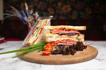 juicy crispy sandwich with ham and vegetables close-up on the board