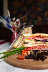 sandwich of bread toasts and vegetables on a wooden board