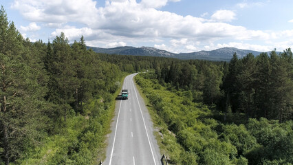 Obraz premium Top view of passing car on highway in forest. Scene. Beautiful view of country road with forest on sunny day. Trip out of town
