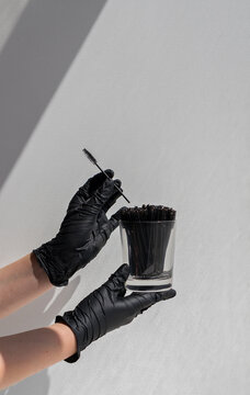 beauty concept. Hands in black gloves holding brushes for lashes
