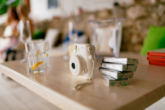 Tivat, Montenegro - 15 april 2021: Fujifilm Instax Square SQ1 white camera with spare film cartridges stands on a wooden table