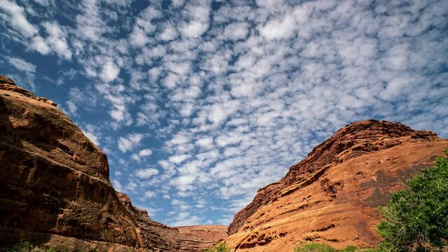 Timelapse of clouds moving over Hog Canyon in the Utah desert as cliffs glow in the sunlight.
