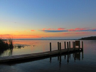 An orange sunrise remains in a blue sky over a dock on Michigan's Muskegon Lake