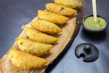 corn empanada typical Colombian food with spicy sauce on a wooden log