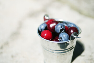 Close up Cherries and blueberries in metal bucket. Fresh berries harvest. Seasonal vitamin food 