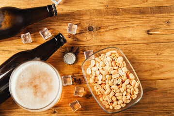 Glass and bottle of beer with wheat ears on wooden planks