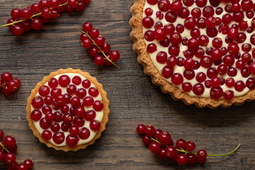 rote Johannisbeeren und Pudding in Törtchen auf Tisch aus Holz
