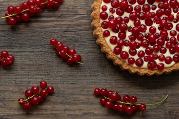 rote Johannisbeeren und Pudding in Törtchen auf Tisch aus Holz