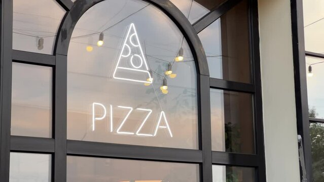 Pizzeria showcase window with pizza sign. View from the street