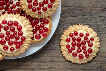 rote Johannisbeeren und Pudding in Törtchen auf Tisch aus Holz