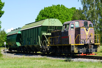 Fototapeta premium a small shunting diesel locomotive pulls two bulk wagons