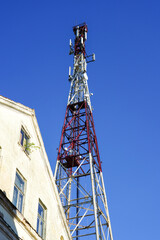 Fototapeta na wymiar High telecommunication tower in city with TV antennas and satellite dishes on blue sky background