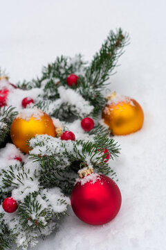 Vertical top view photo of the coniferous branches decorated with toys for the Christmas tree lie in the snow