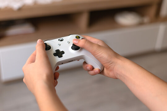 Krasnodar, Russia-October 23, 2021: a girl is playing xbox at home. she is holding a gaypad in her hands