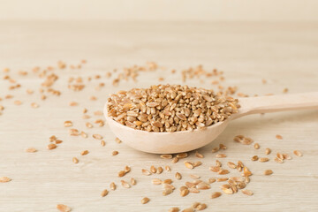 Spoon with wholegrain spelt farro on wooden table