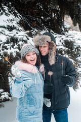 Fototapeta na wymiar Young beautiful couple in winter forest. Happy couple has fun with snow.