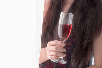Hispanic beautiful woman enjoying her morning, comfortable at home wearing red lingerie and drinking red wine from a crystal glass