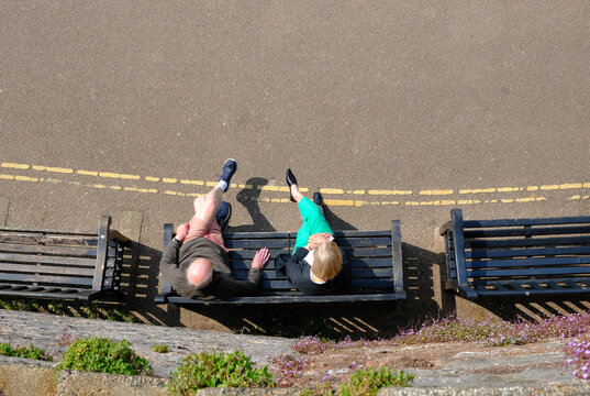 Topsham/England-May 2020: Senior Caucasian Couple Relax Sitting On A Bench, View From Above